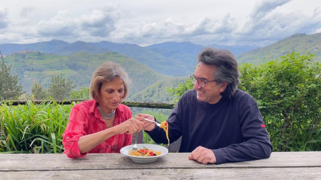 Celia and Enzo sharing a plate in front of countryside